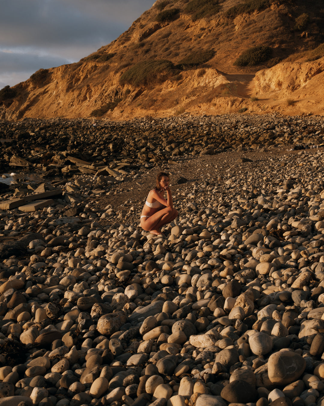 A swimmer resting on a stony shore